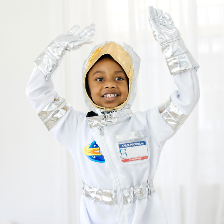 A kid playing with the Melissa & Doug Astronaut Costume Role Play Space Set (5 pcs) - Jumpsuit, Helmet, Gloves, Name Tag