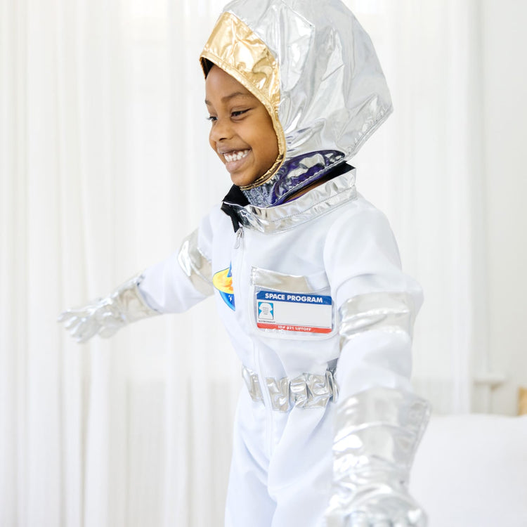 A kid playing with the Melissa & Doug Astronaut Costume Role Play Space Set (5 pcs) - Jumpsuit, Helmet, Gloves, Name Tag