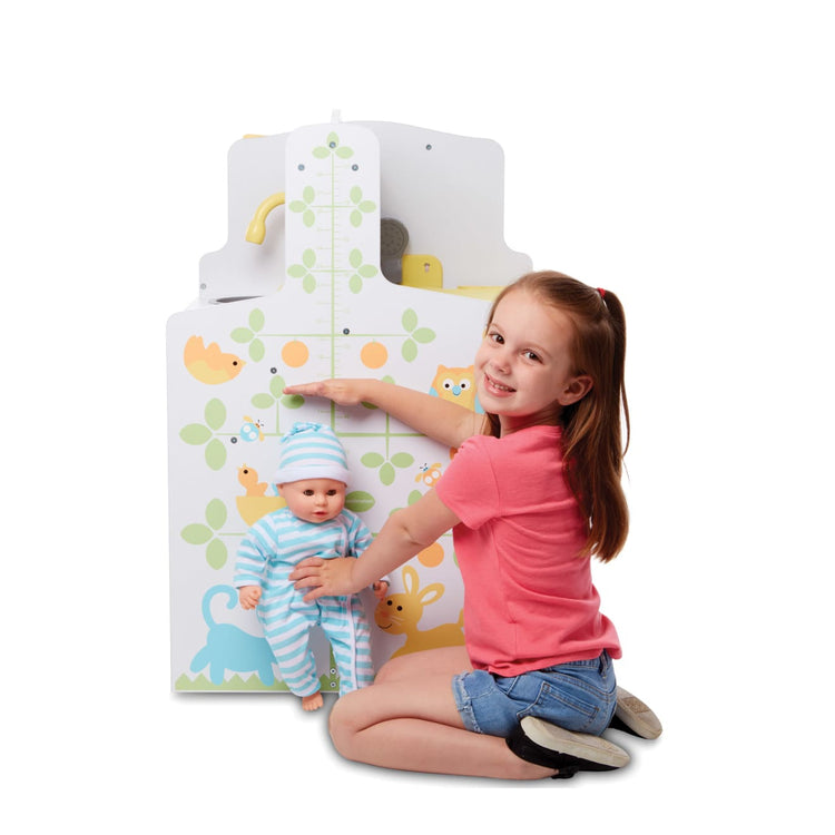 A child on white background with the Melissa & Doug Mine to Love Baby Care Activity Center for Dolls - Kitchen, Nursery, Bathing-Changing
