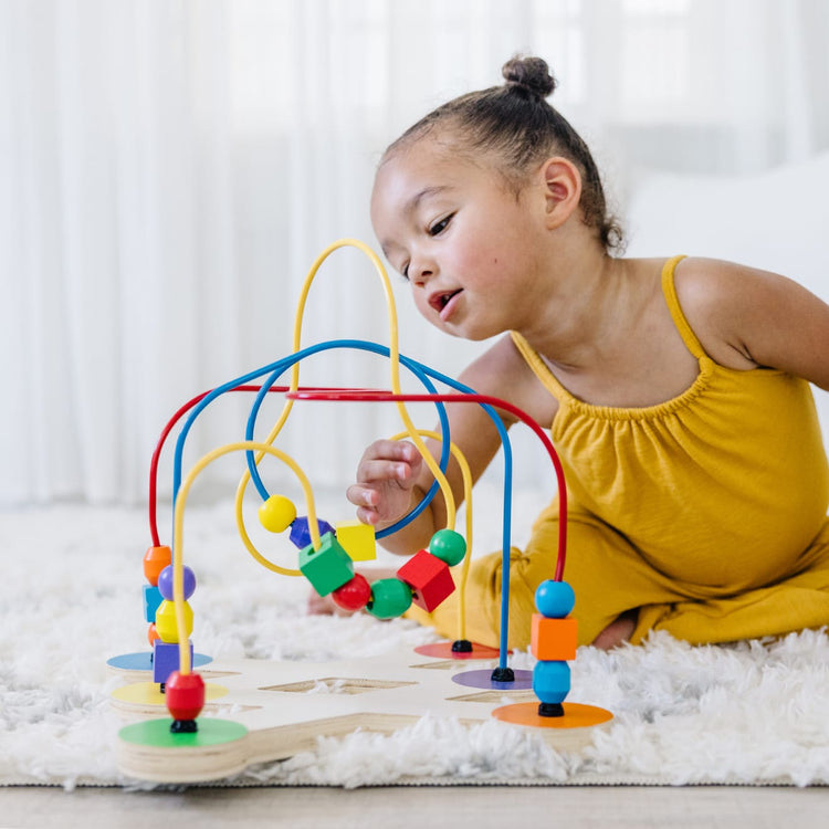 A kid playing with the Melissa & Doug Classic Bead Maze - Wooden Educational Toy