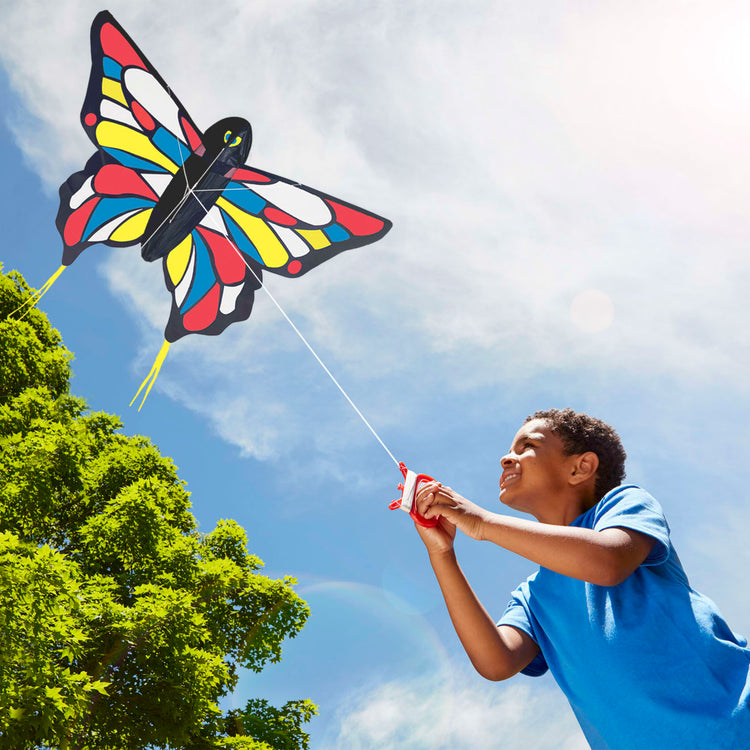 A kid playing with the Melissa & Doug Beautiful Butterfly Single Line Shaped Kite (50-Inch Wingspan)