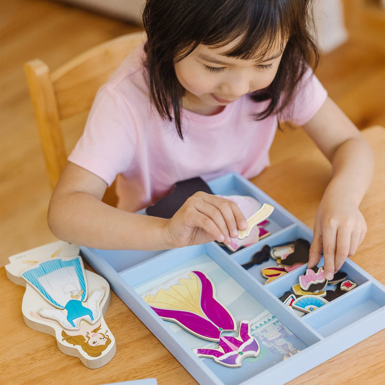 A kid playing with the Melissa & Doug Disney Belle Magnetic Dress-Up Wooden Doll Pretend Play Set