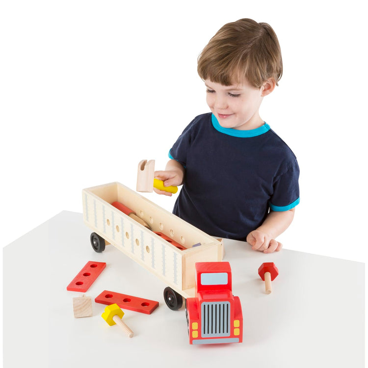 A child on white background with the Melissa & Doug Big Rig Truck Wooden Building Set (22 pcs)