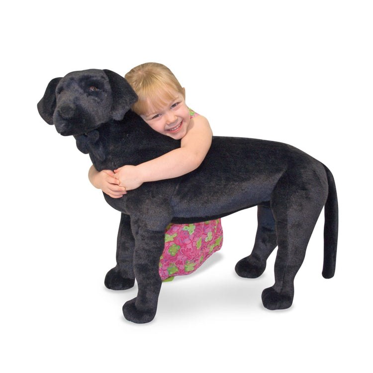 A child on white background with the Melissa & Doug Giant Black Lab - Lifelike Stuffed Animal Dog (over 2 feet tall)
