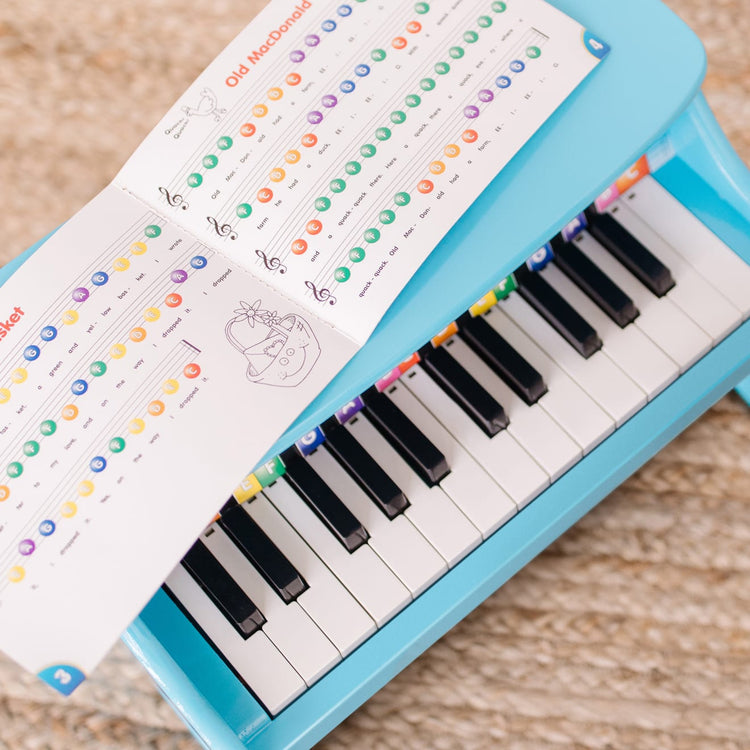 A kid playing with the Melissa & Doug Learn-to-Play Piano With 25 Keys and Color-Coded Songbook - Blue