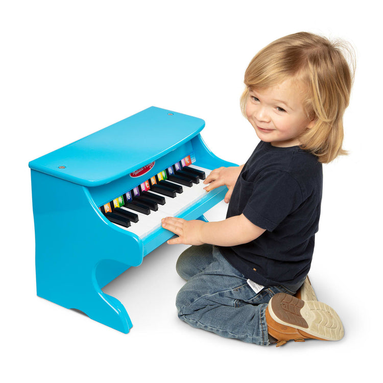 A child on white background with the Melissa & Doug Learn-to-Play Piano With 25 Keys and Color-Coded Songbook - Blue