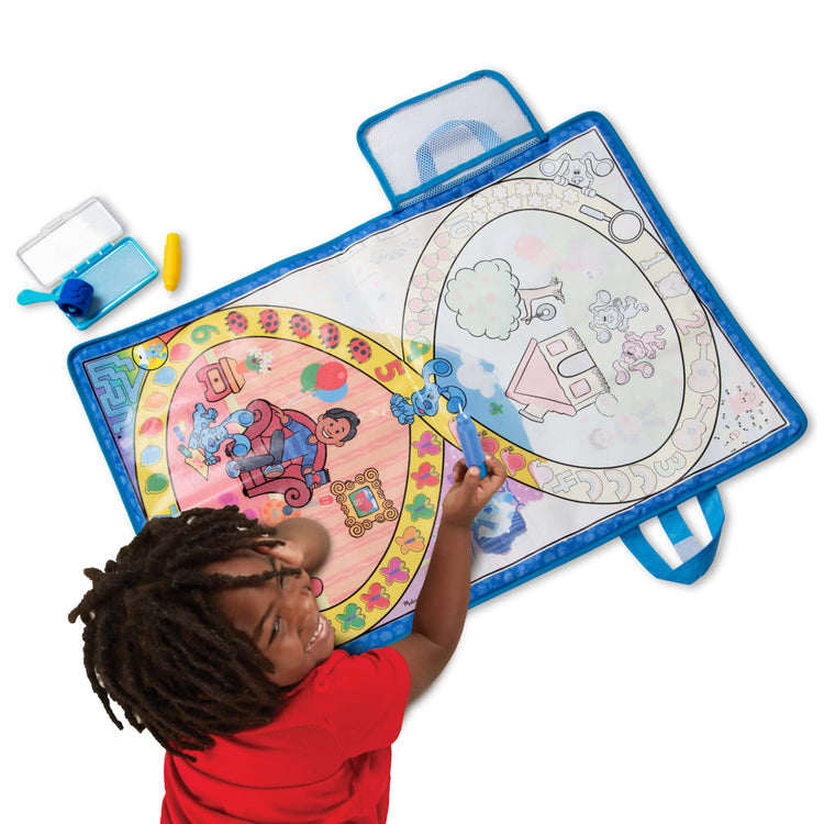 A child on white background with the Melissa & Doug Blue's Clues & You! Water Wow! Activity Mat (20 Inches x 30 Inches) With Reusable Water Reveal Surface
