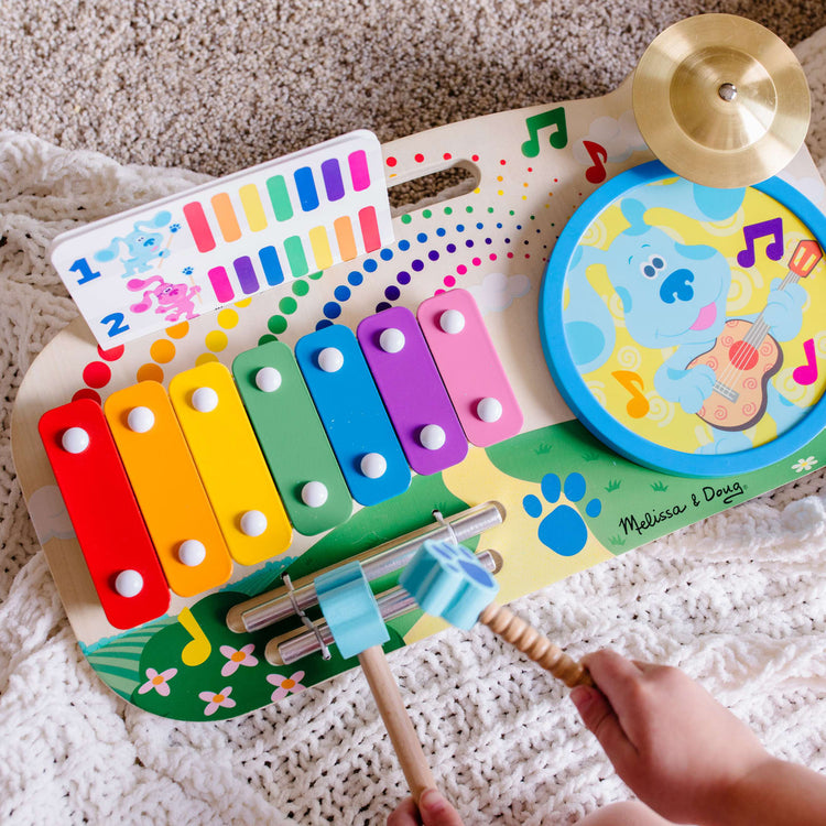 A kid playing with the Melissa & Doug Blue's Clues & You! Wooden Music Maker Board (5 Instruments)