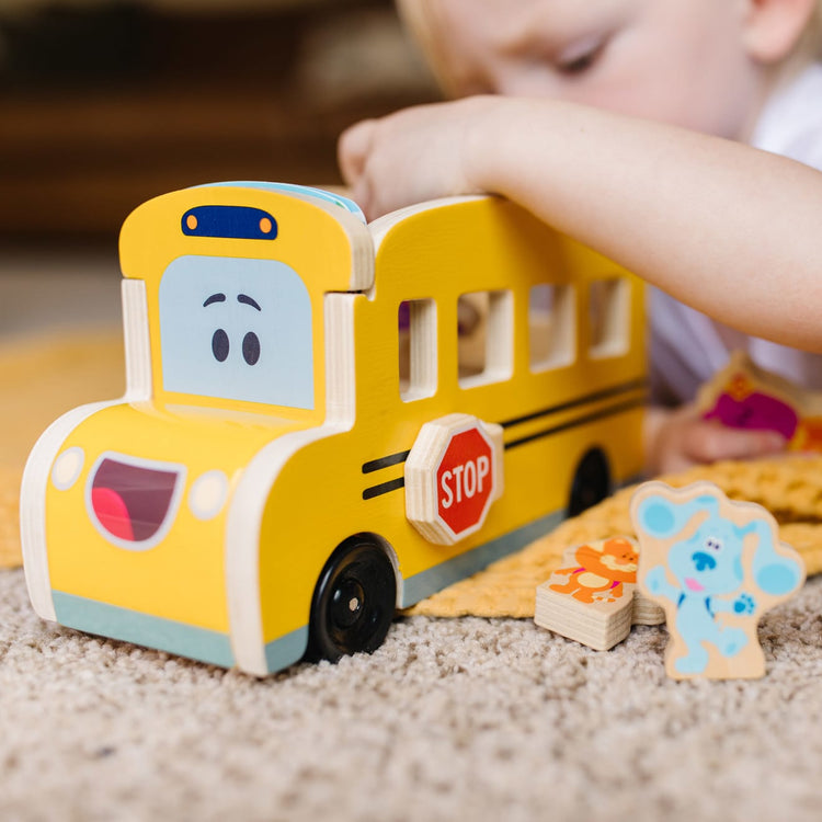 A kid playing with the Melissa & Doug Blue's Clues & You! Wooden Pull-Back School Bus (9 Pieces)