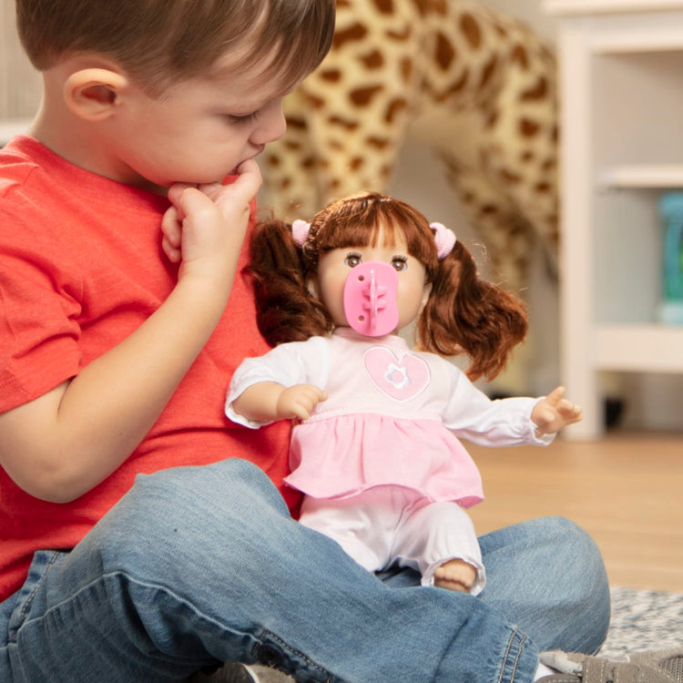 A kid playing with the Melissa & Doug Mine to Love Brianna 12-Inch Soft Body Baby Doll With Hair and Outfit