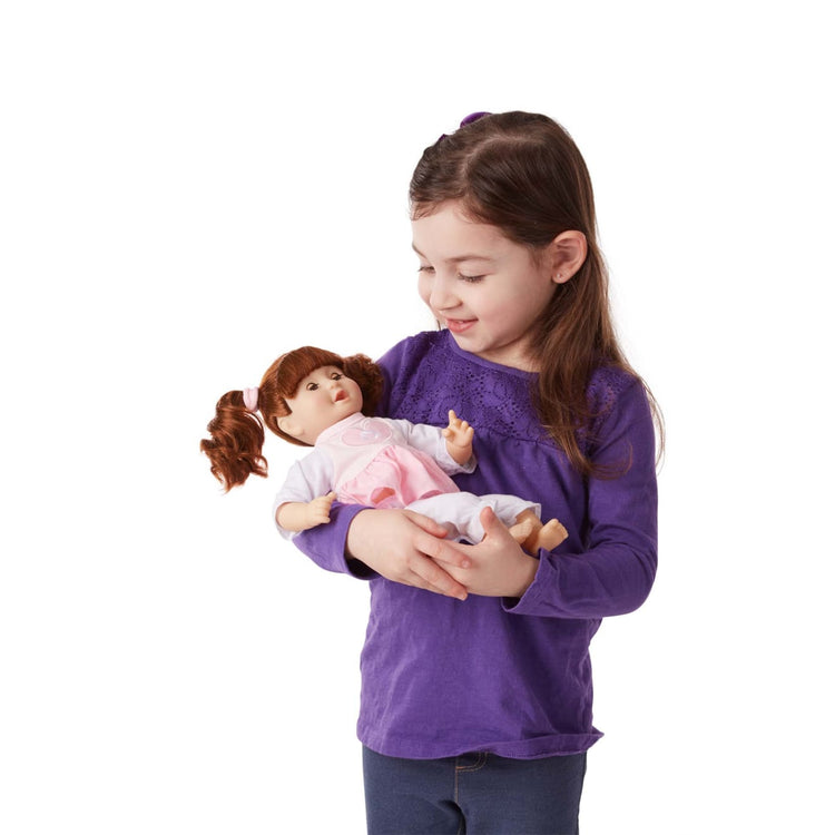 A child on white background with the Melissa & Doug Mine to Love Brianna 12-Inch Soft Body Baby Doll With Hair and Outfit