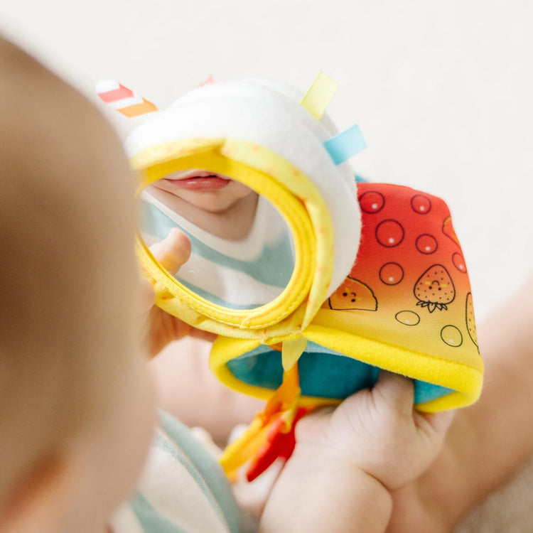 A kid playing with the Melissa & Doug Multi-Sensory Bubble Tea Take-Along Clip-On Infant Toy