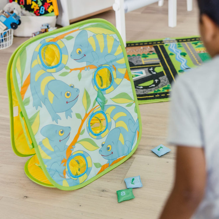 A kid playing with the Melissa & Doug Sunny Patch Camo Chameleon Bean Bag Toss Action Game