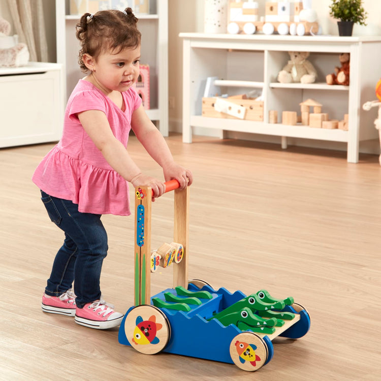 A kid playing with the Melissa & Doug Deluxe Chomp and Clack Alligator Wooden Push Toy and Activity Walker