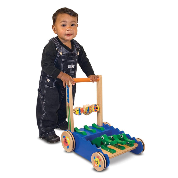 A child on white background with the Melissa & Doug Deluxe Chomp and Clack Alligator Wooden Push Toy and Activity Walker