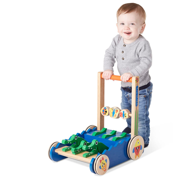 A child on white background with the Melissa & Doug Deluxe Chomp and Clack Alligator Wooden Push Toy and Activity Walker