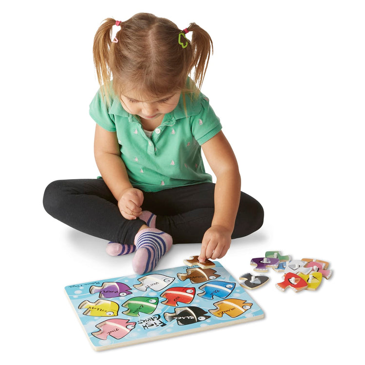 A child on white background with the Melissa & Doug Classic Wooden Peg Puzzles (Set of 3) - Numbers, Alphabet, and Colors