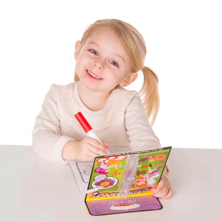 A child on white background with the Melissa & Doug On the Go ColorBlast! Activity Book: Fairy - 24 Pictures and No-Mess Pen