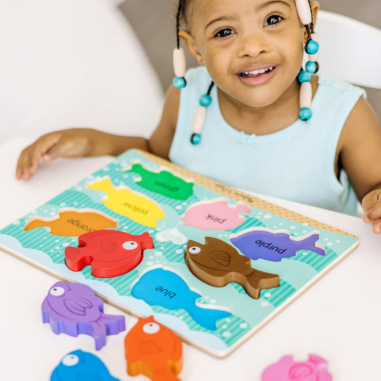 A kid playing with the Melissa & Doug Colorful Fish Wooden Chunky Puzzle (8 pcs)