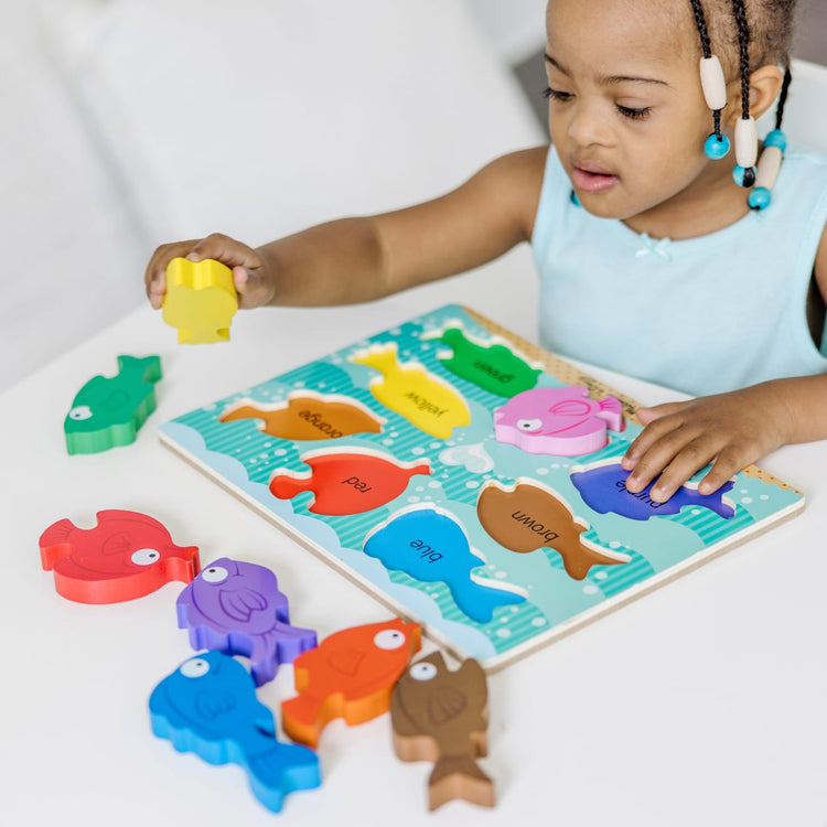 A kid playing with the Melissa & Doug Colorful Fish Wooden Chunky Puzzle (8 pcs)