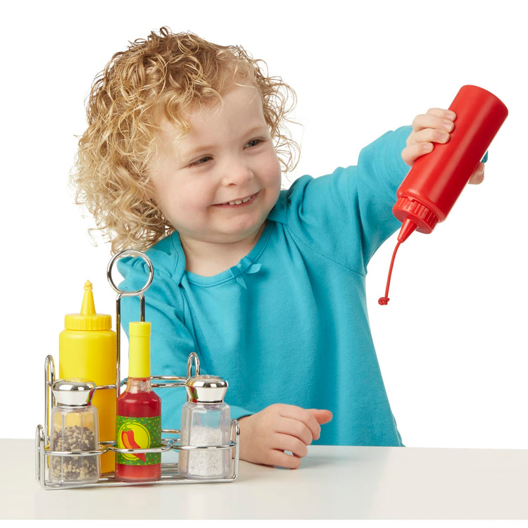 A child on white background with the Melissa & Doug Condiments Play Set (6 pcs) - Play Food, Stainless Steel Caddy