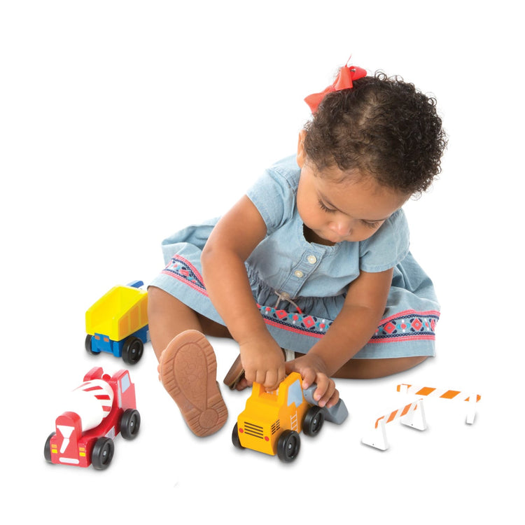 A child on white background with the Melissa & Doug Construction Vehicle Wooden Play Set (8 pcs)