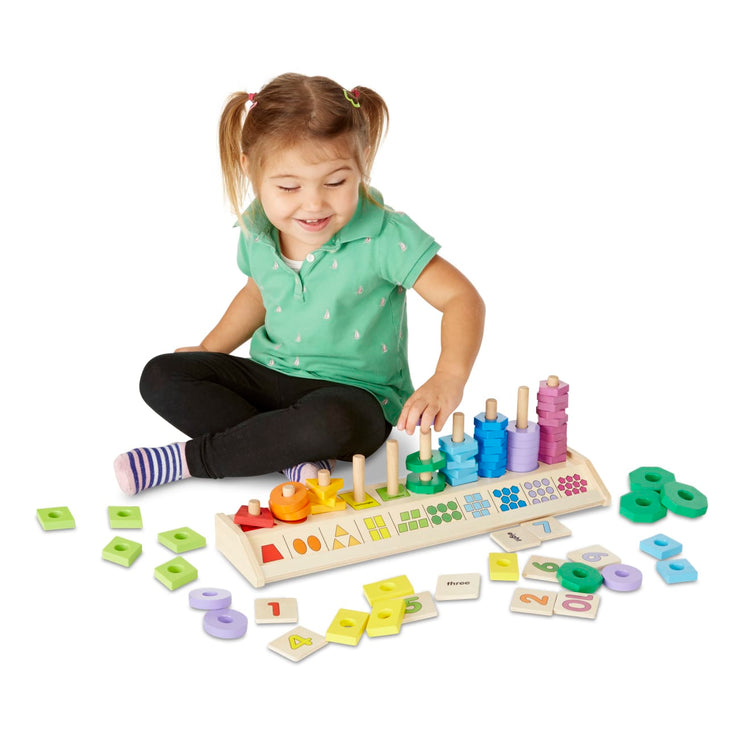 A child on white background with the Melissa & Doug Counting Shape Stacker - Wooden Educational Toy With 55 Shapes and 10 Number Tiles