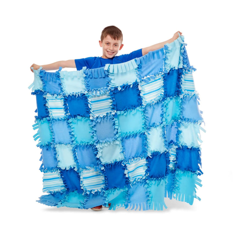 A child on white background with the Melissa & Doug Created by Me! Striped Fleece Quilt No-Sew Craft Kit (48 squares, 4 feet x 5 feet)