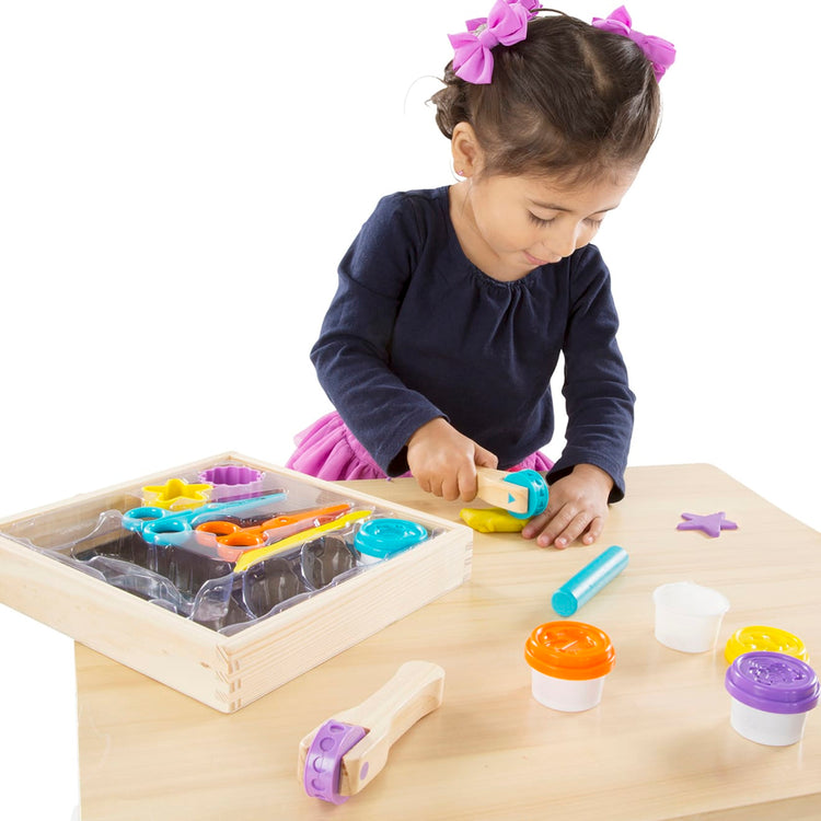 A child on white background with the Melissa & Doug Created by Me! Cut, Sculpt, and Roll Modeling Dough Kit With 8 Tools and 4 Colors of Modeling Dough
