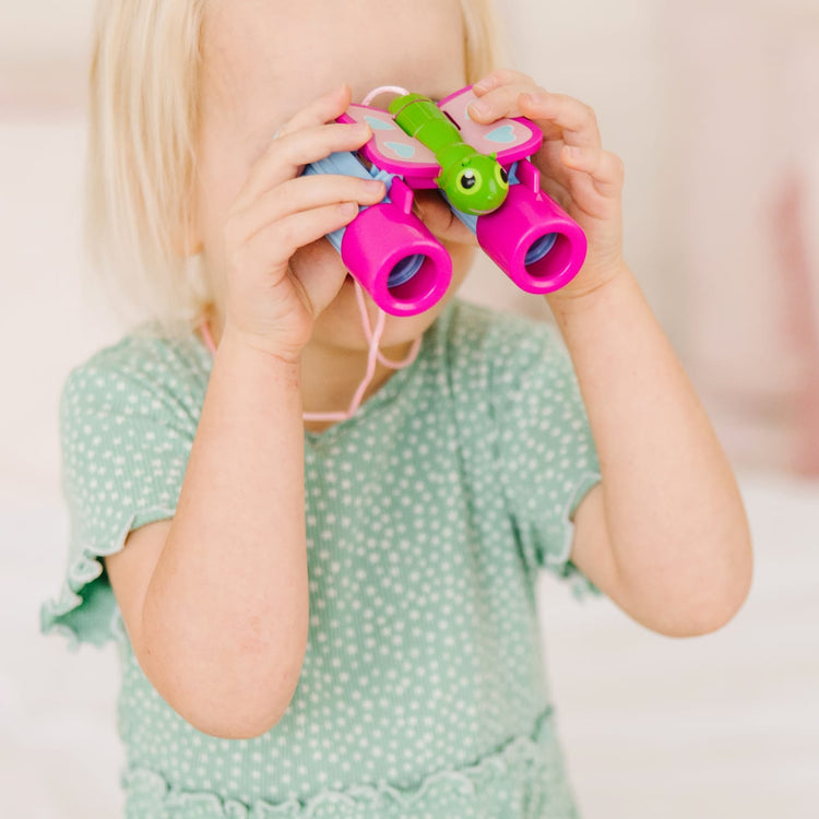 A kid playing with the Melissa & Doug Sunny Patch Cutie Pie Butterfly Binoculars - Pretend Play Toy