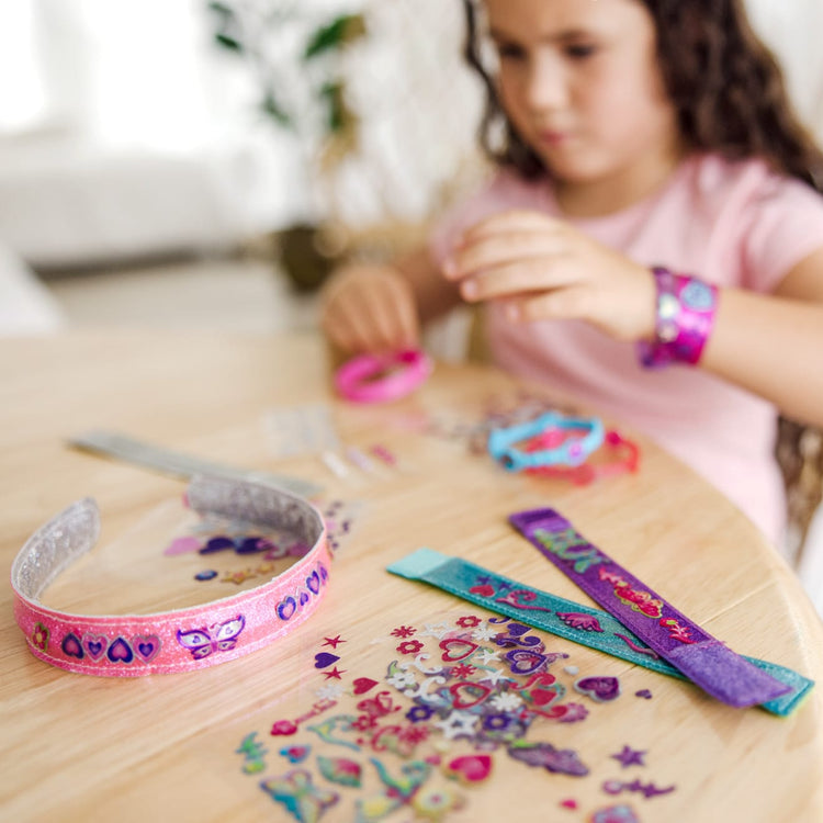 A kid playing with the Melissa & Doug Design-Your-Own Jewelry-Making Kits - Bangles, Headbands, and Bracelets