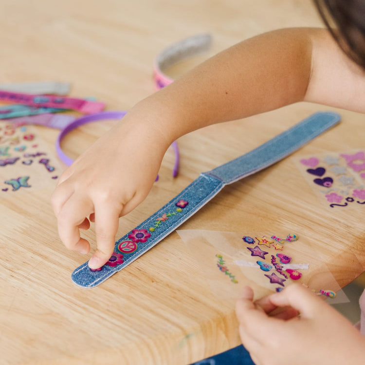 A kid playing with the Melissa & Doug Design-Your-Own Jewelry-Making Kits - Bangles, Headbands, and Bracelets