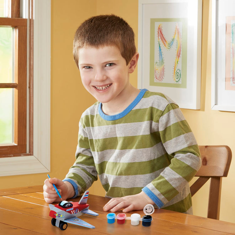 A kid playing with the Melissa & Doug Decorate-Your-Own Wooden Plane Craft Kit