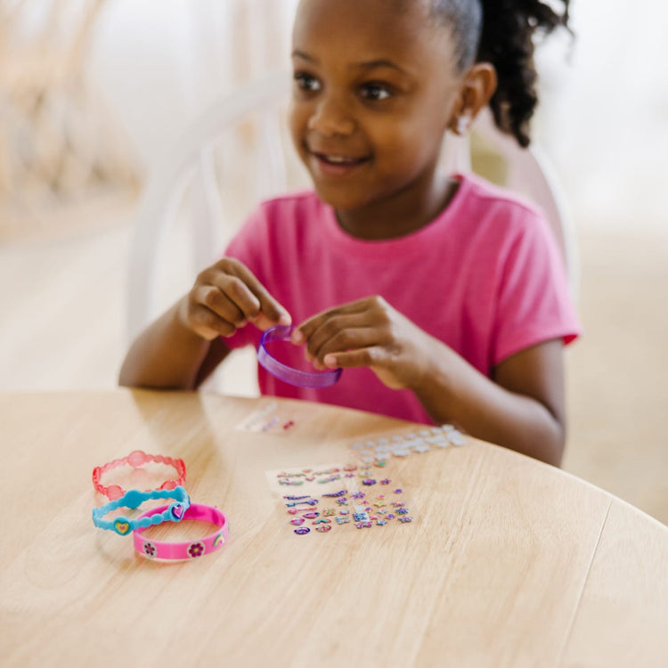 A kid playing with the Melissa & Doug Design-Your-Own Bangles Bracelet-Making Set (Makes 4 Bangles)