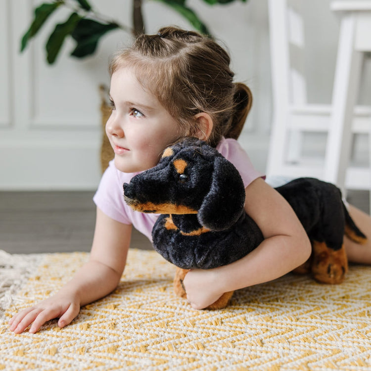 A kid playing with the Melissa & Doug Giant Dachshund - Lifelike Stuffed Animal Dog
