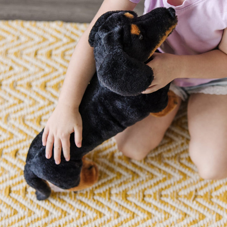 A kid playing with the Melissa & Doug Giant Dachshund - Lifelike Stuffed Animal Dog