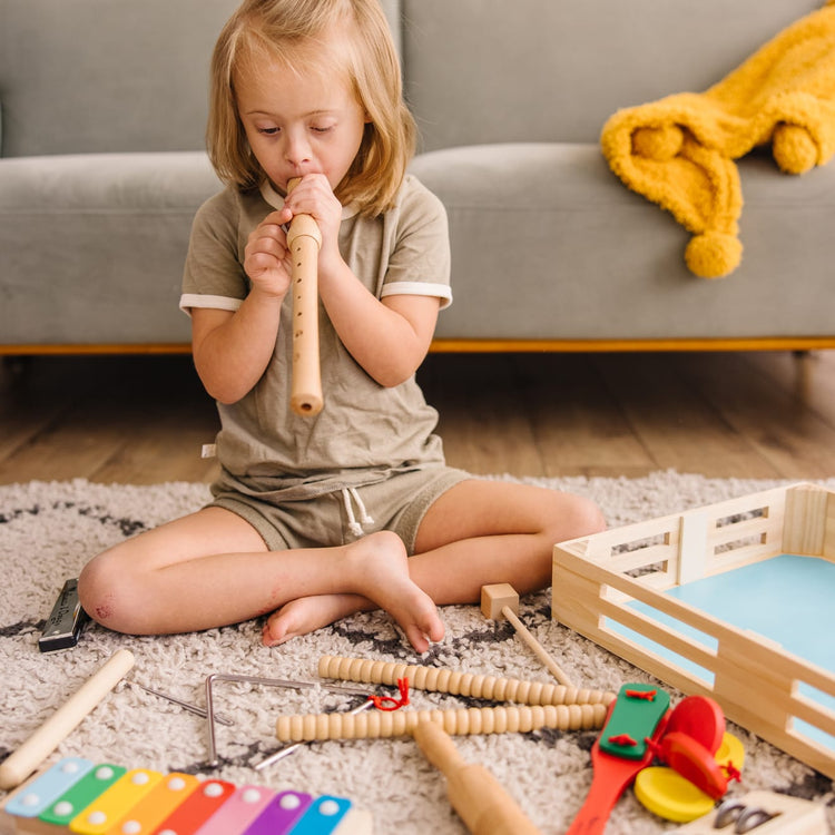 A kid playing with the Melissa & Doug Deluxe Band Set With Wooden Musical Instruments and Storage Case