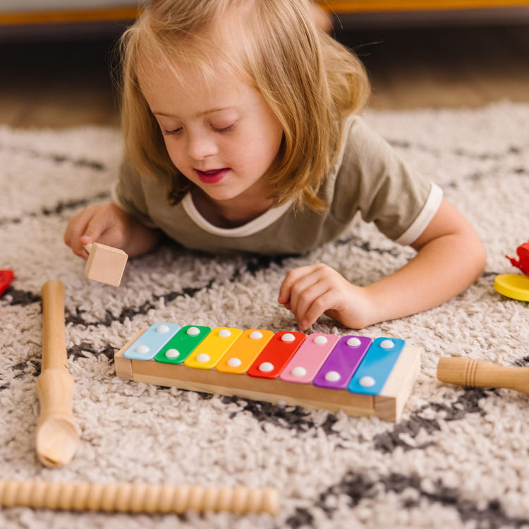 A kid playing with the Melissa & Doug Deluxe Band Set With Wooden Musical Instruments and Storage Case