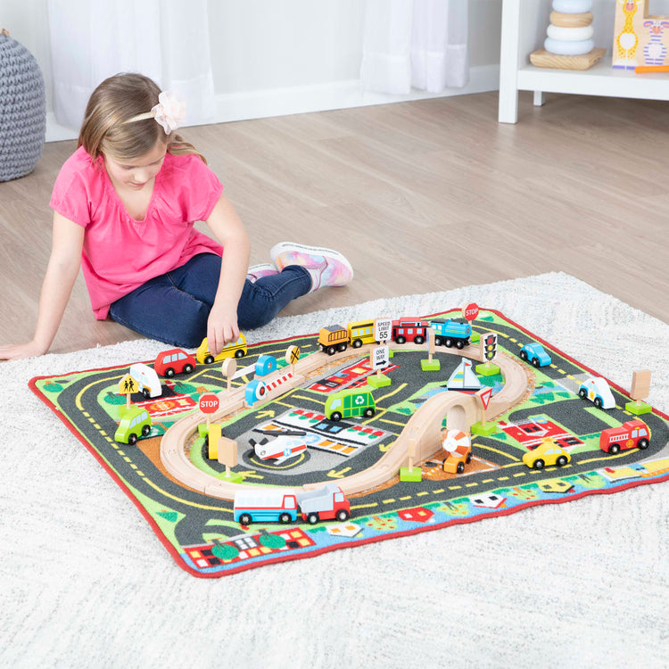 A kid playing with the Melissa & Doug Deluxe Multi-Vehicle Activity Rug (39.5" x 36.5") - 19 Vehicles, 12 Wooden Signs, Train Tracks