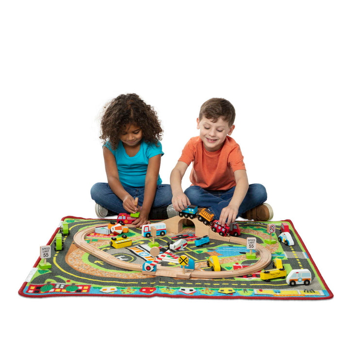A child on white background with the Melissa & Doug Deluxe Multi-Vehicle Activity Rug (39.5" x 36.5") - 19 Vehicles, 12 Wooden Signs, Train Tracks