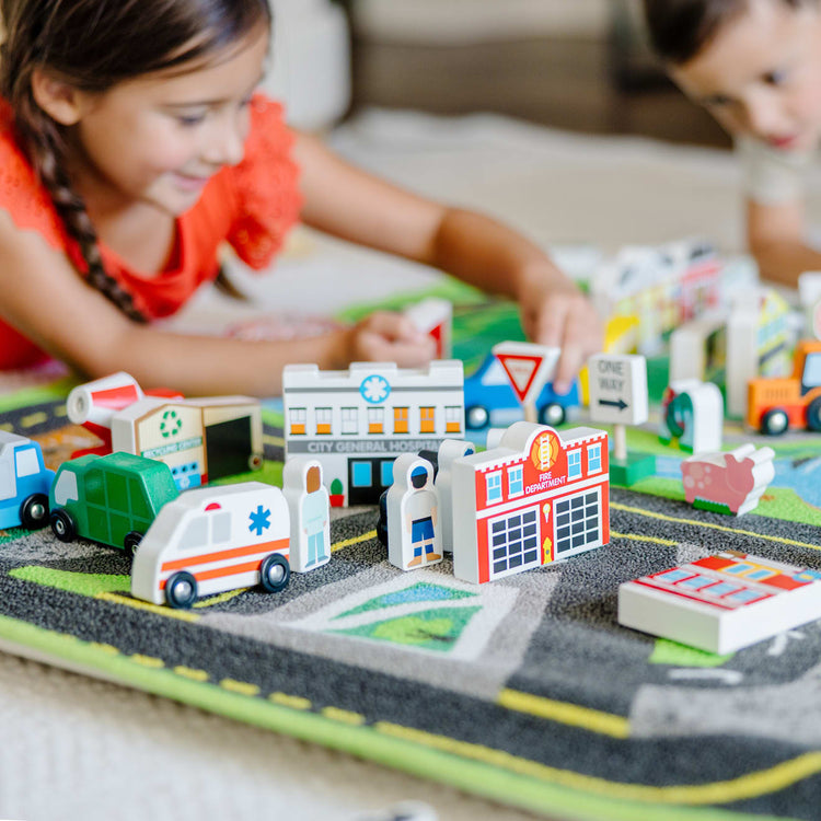 A kid playing with the Melissa & Doug Deluxe Activity Road Rug Play Set with 49 Wooden Vehicles and Play Pieces
