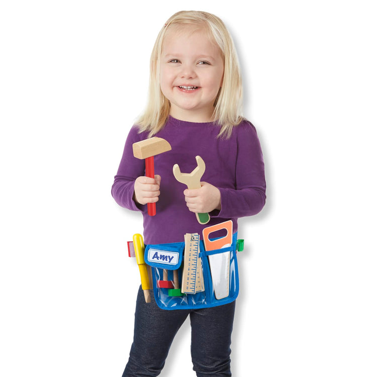 A child on white background with the Melissa & Doug Deluxe Tool Belt Set - 5 Wooden Tools, 8 Building Pieces, Adjustable Belt