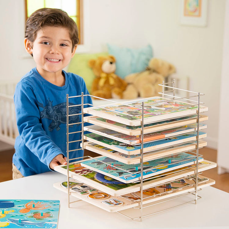 A kid playing with the Melissa & Doug Deluxe Metal Wire Puzzle Storage Rack for 12 Small and Large Puzzles