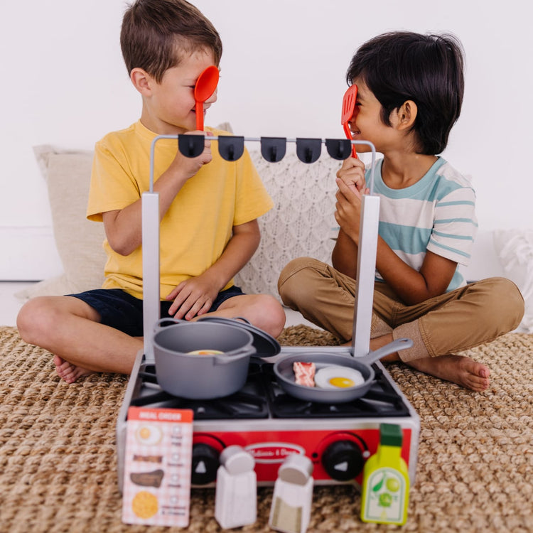 A kid playing with the Melissa & Doug 19-Piece Deluxe Wooden Cooktop Set With Wooden Play Food, Durable Pot and Pan