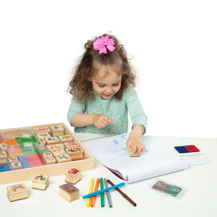 A child on white background with the Melissa & Doug Deluxe Wooden Stamp Set: Animals - 30 Stamps, 6 Markers, 2 Stamp Pads