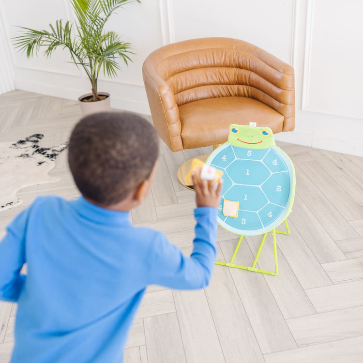 A kid playing with the Melissa & Doug Sunny Patch Dilly Dally Turtle Target Action Game