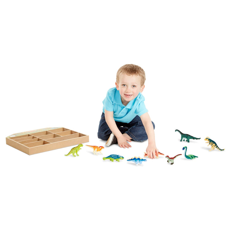 A child on white background with the Melissa & Doug Dinosaur Party Play Set - 9 Collectible Miniature Dinosaurs in a Case