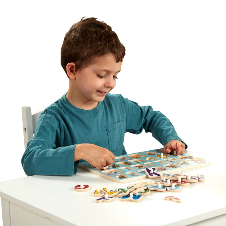 A child on white background with the Melissa & Doug Disney Classics Alphabet Wooden Peg Puzzle (26 pcs)