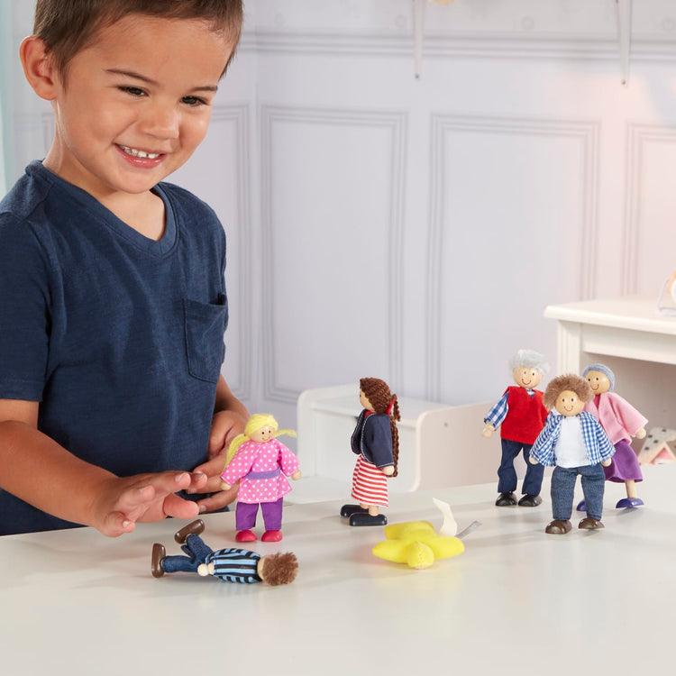 A kid playing with the Melissa & Doug 7-Piece Poseable Wooden Doll Family for Dollhouse (2-4 inches each)