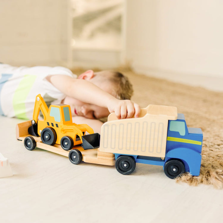 A kid playing with the Melissa & Doug Classic Toy Wooden Dump Truck & Loader with Construction Pieces